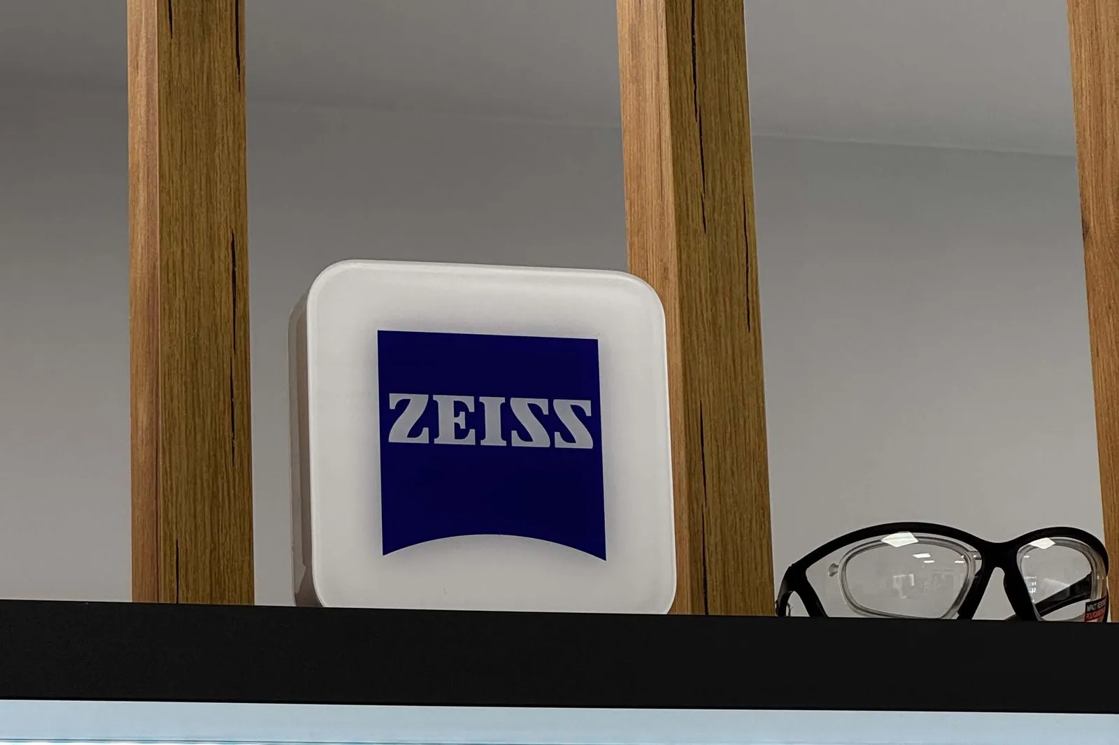 Podświetlany kaseton z logo ZEISS nad ekspozycją opraw w salonie Optyk Bryle w Koluszkach